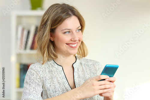 Happy woman looking at side holding a mobile phone