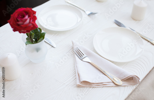 Romantic dinner concept. Valentine day or proposal background. Top view of restaurant wooden table with heart and rose with cutlery on plate. Copy space on rustic wood