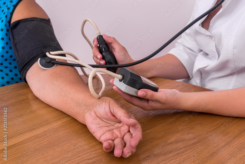 Doctor's and patient's hands with tonometer measuring blood pressure