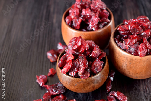 Dried cranberries in wooden bowls against the dark background