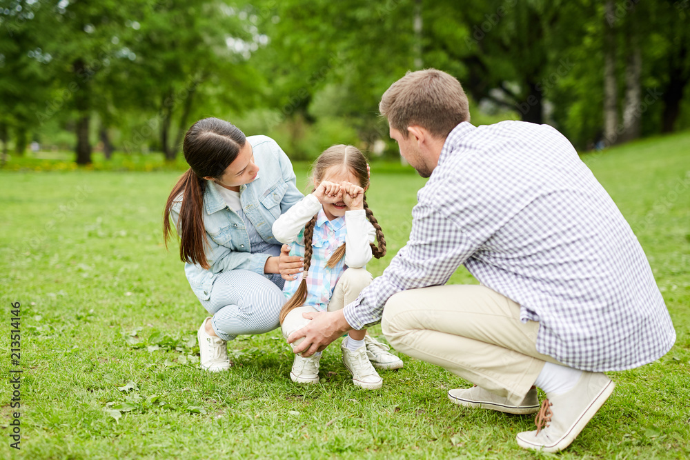 Young father and mother supporting their sad little daughter during chill in park Young father and mother supporting their sad little daughter during chill in park