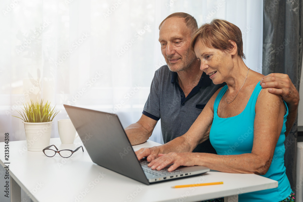 senior couple using laptop computer together at home senior couple using laptop computer together at home