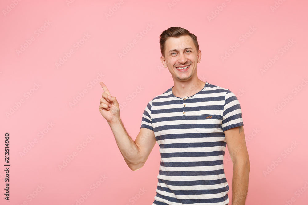 Portrait excited smiling young man wearing striped t-shirt pointing index finger aside on copy space isolated on trending pink background. People sincere emotions lifestyle concept. Advertising area. Portrait excited smiling young man wearing striped t-shirt pointing index finger aside on copy space isolated on trending pink background. People sincere emotions lifestyle concept. Advertising area.
