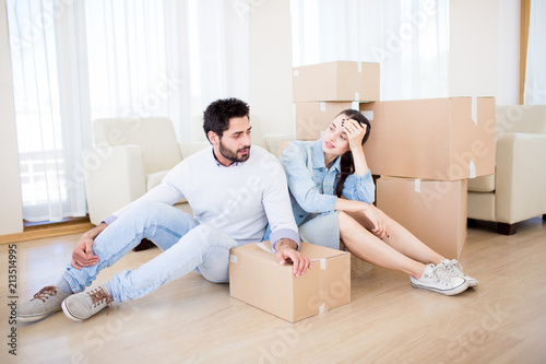 Young couple having rest on the floor of their new house by stack of boxes © pressmaster