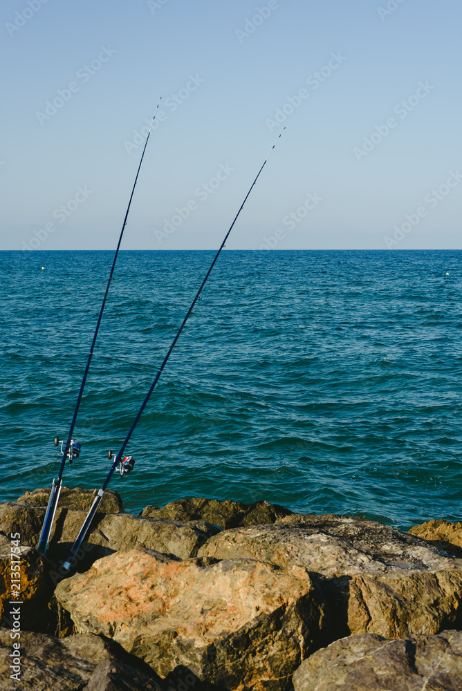 Fishing rods fixed to the rocks near the sea coast without fishermen