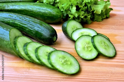 Sliced fresh cucumber on a wooden cutting board  close up.