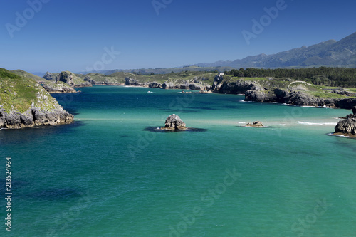 Mar con rocas en un dia soleado con distintos azules