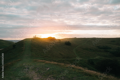 Two people watching the sunset from the hills 