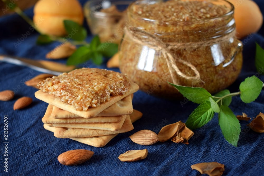 Fototapeta premium Urbech of apricot kernels in a glass jar and on a cracker