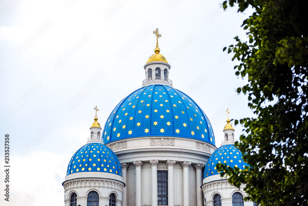 Construction of white brick with dark room. Traffic lights on the sidewalk. Blue Church domes with crosses. Against the blue sky