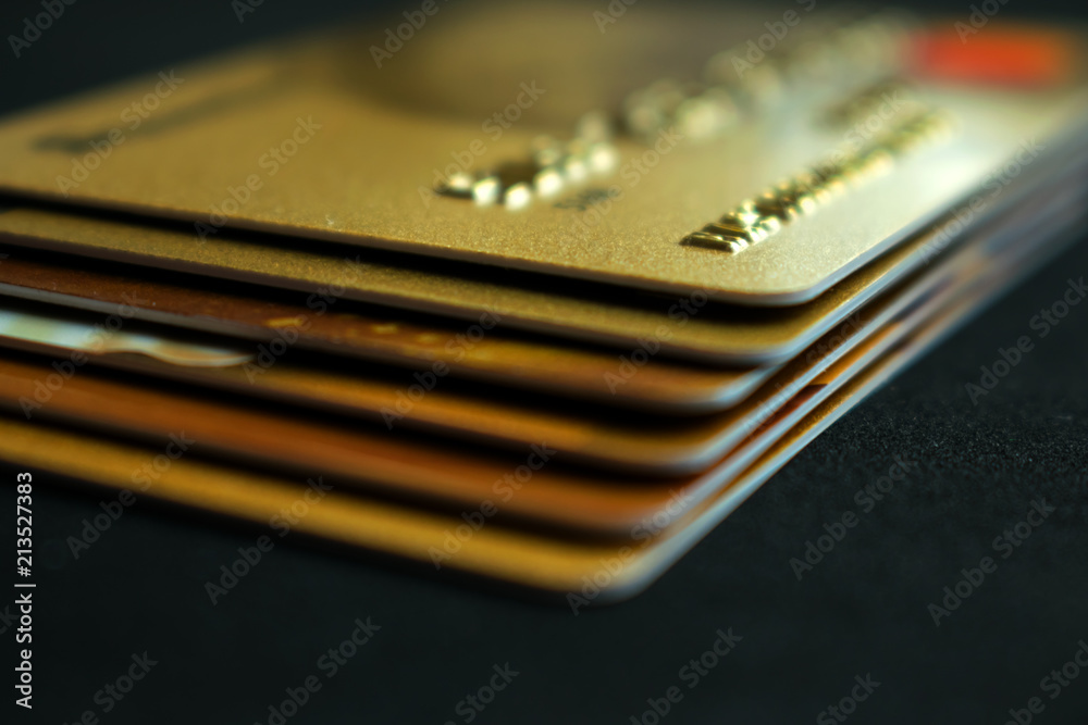 Stack of gold credit cards on dark background, close up view with selective focus. Different VIP credit cards, background with copy space. Paying, Buying. Stack of gold credit cards on dark background, close up view with selective focus. Different VIP credit cards, background with copy space. Paying, Buying.