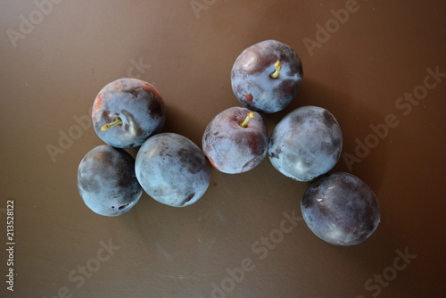 Fresh ripped plums on a brown matte background