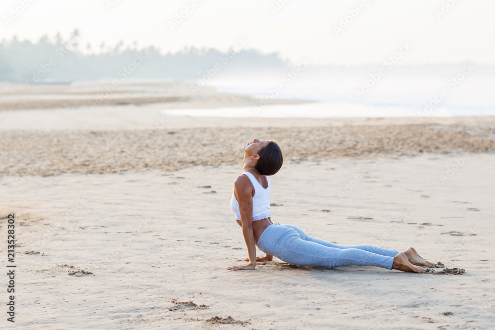 Caucasian woman practicing yoga at seashore of tropic ocean Caucasian woman practicing yoga at seashore of tropic ocean