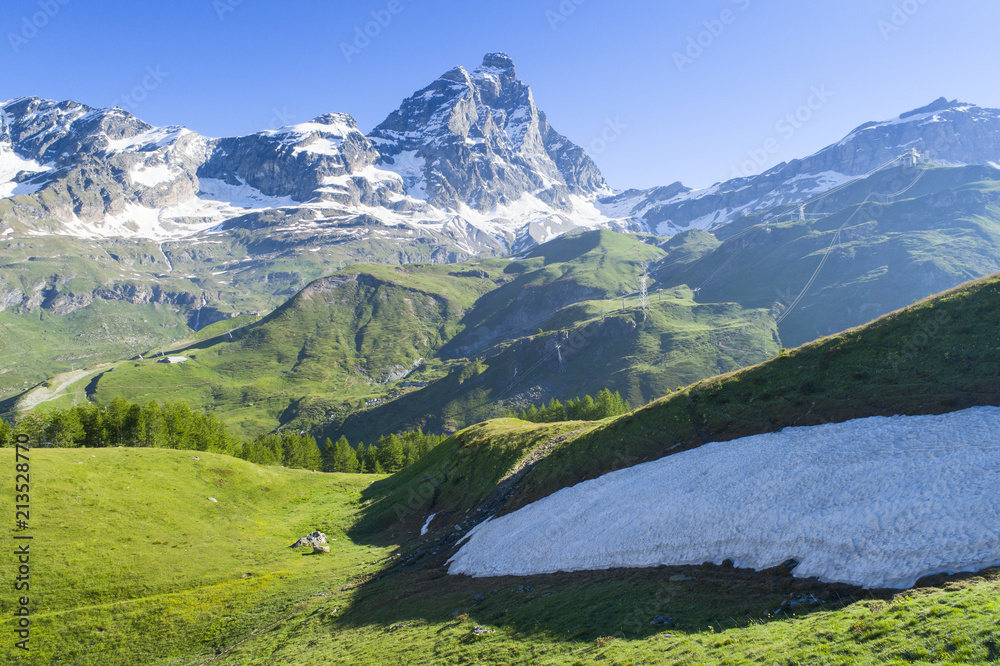 green hills with snow in view to Alps peak in Italy