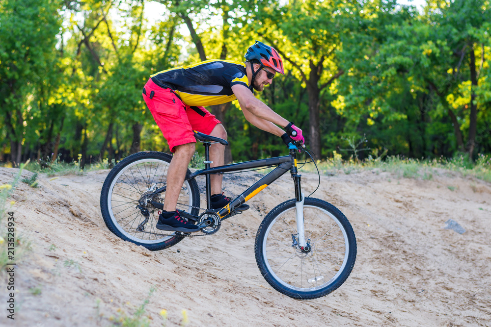 Naklejka premium Professional cyclist descending from the top on a mountain bike, an extreme sport.