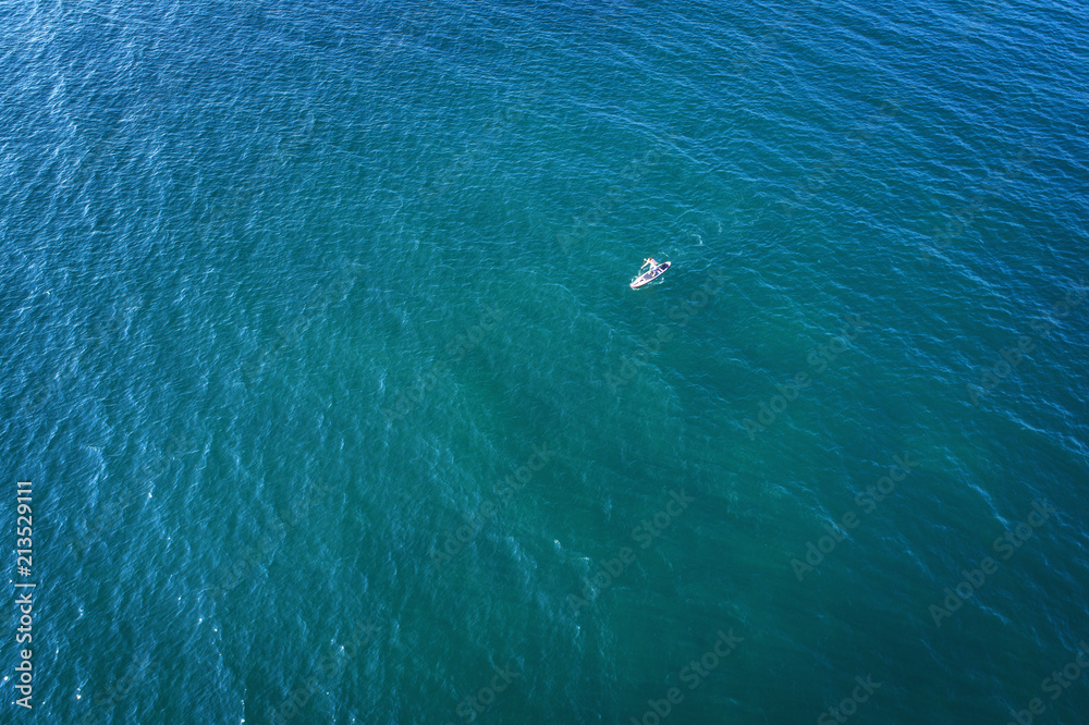 aerial view to alone surfer in the blue sea aerial view to alone surfer in the blue sea