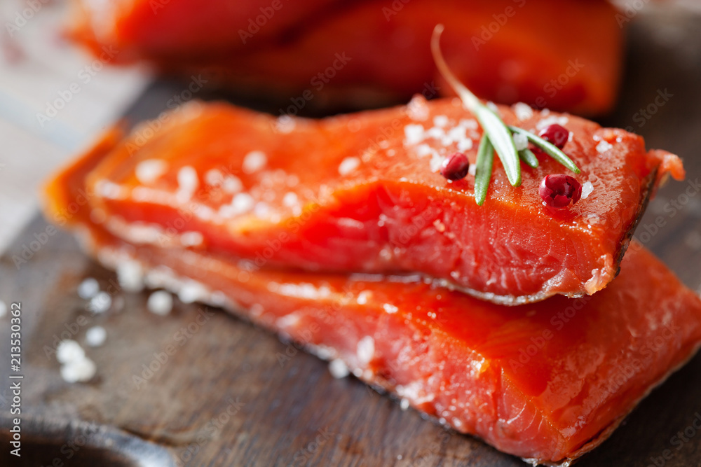 Smoked salmon fillet with pepper, salt, rosemary and lemon and rosemary on wooden table Smoked salmon fillet with pepper, salt, rosemary and lemon and rosemary on wooden table