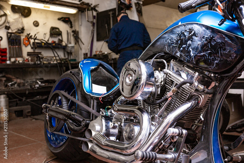 Side view portrait of man working in garage repairing motorcycle and customizing it © Georgii