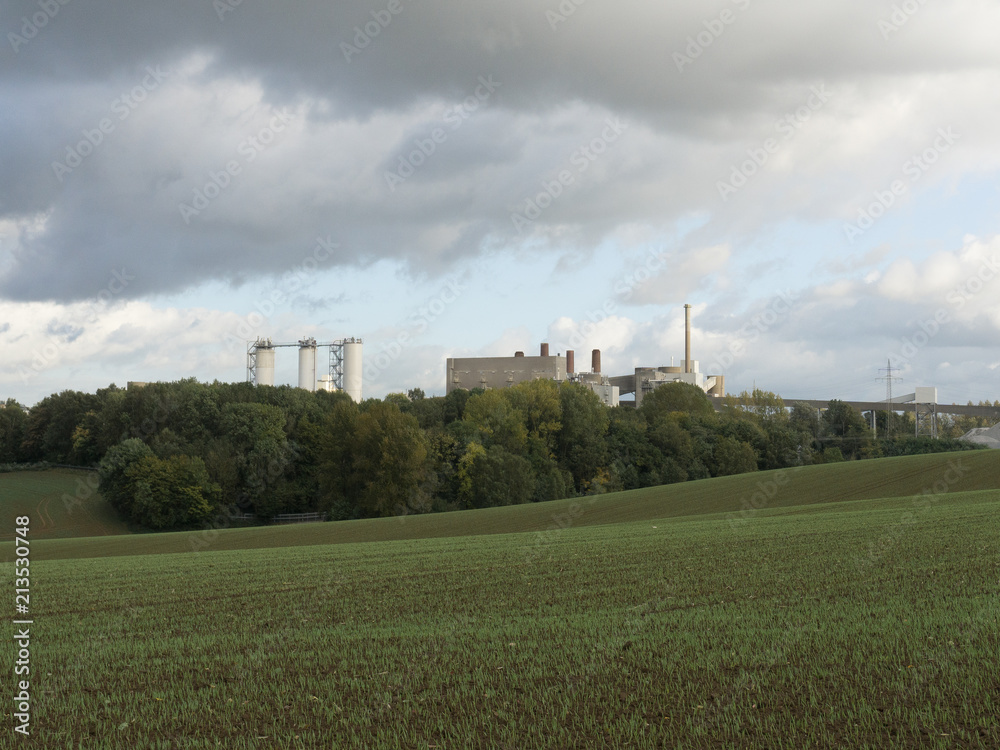 A large modern plant among the forest and green fields outside the city