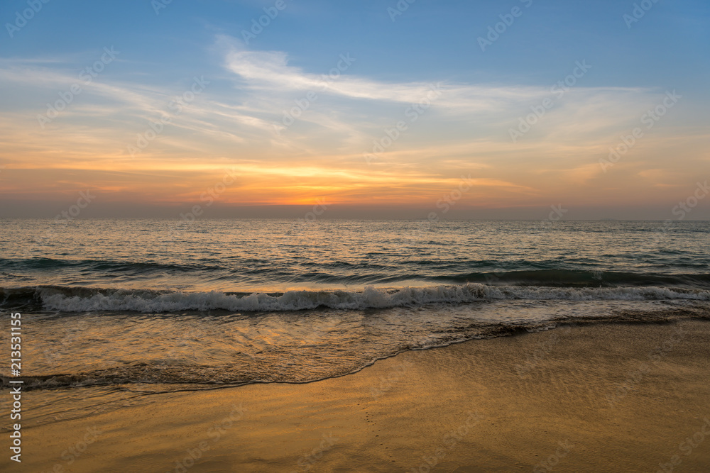 Waves on the beach, sunset, cloudy sky.