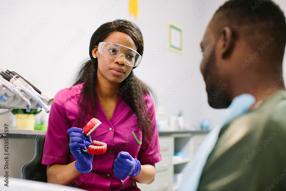 friendly female dentist showing teeth model to his patient friendly female dentist showing teeth model to his patient