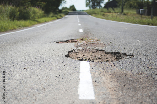 Damaged asphalt pavement road with potholes.