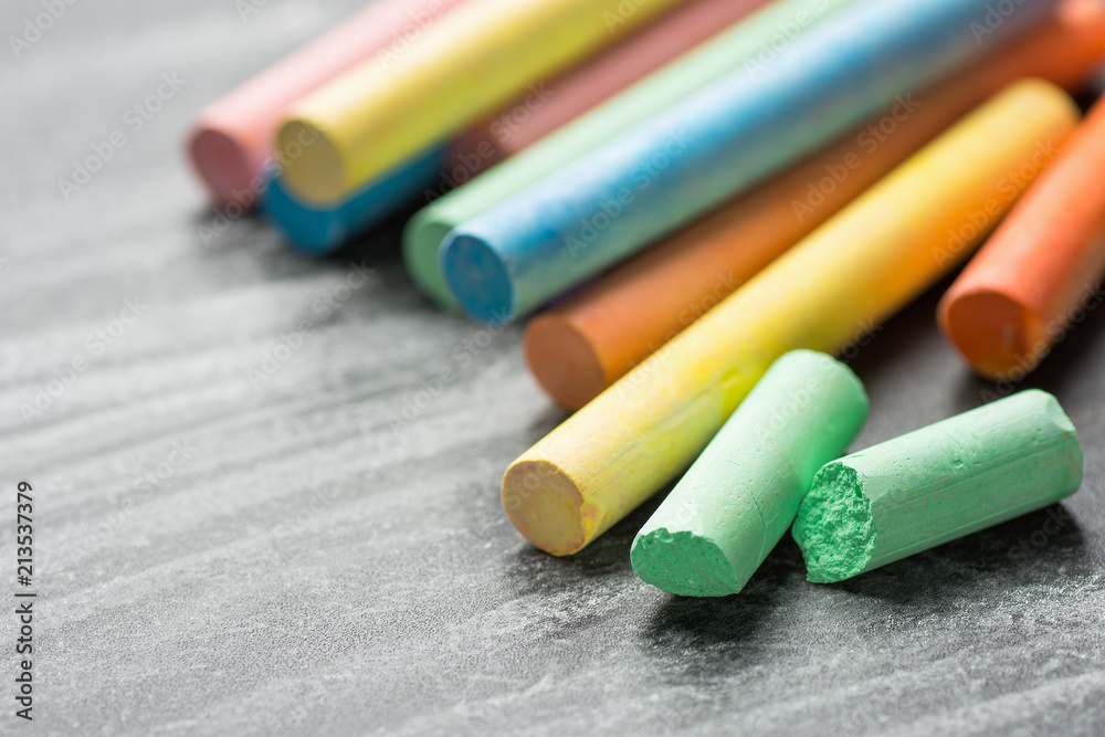 Row Pile of Multicolored Chalks Crayons on Dark Scratched Blackboard. Back to School Business Creativity Graphic Design Crafts Kids Concept. Poster Banner with Copy Space Row Pile of Multicolored Chalks Crayons on Dark Scratched Blackboard. Back to School Business Creativity Graphic Design Crafts Kids Concept. Poster Banner with Copy Space