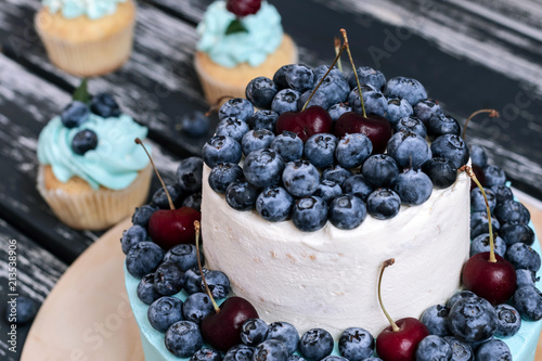 Blueberry cupcakes decorated with cream and fresh berries.
