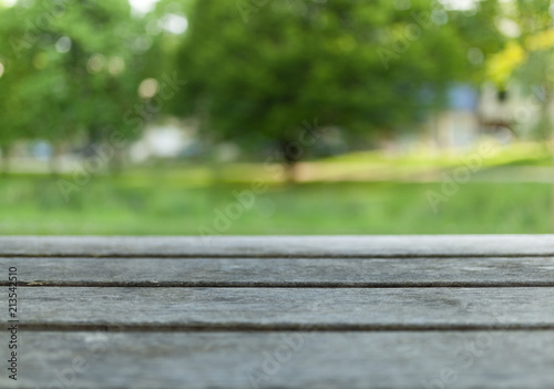 Empty wooden table with blurred city park on background © Andrii
