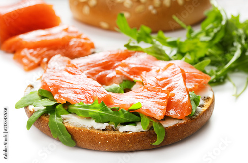 close-up view of bagel sandwich with salmon, arugula and cream cheese isolated on white background