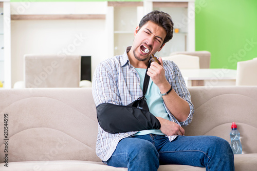 Young student man with hand injury sitting on the sofa  © Elnur