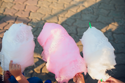 The hands of girl holding pink cotton candy in the background of blue sky photo