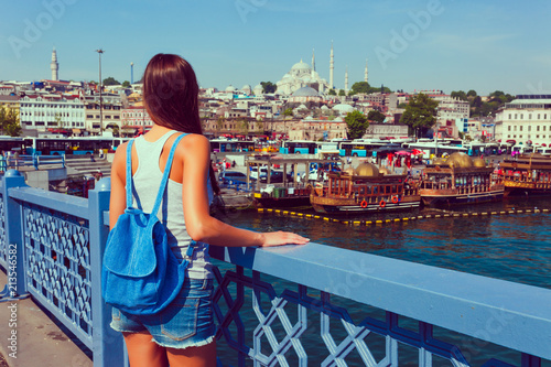Young tourist woman on Galata bridge, Golden Horn bay, Istanbul. Panorama cityscape of famous tourist destination Bosphorus strait channel. Travel landscape Bosporus, Turkey, Europe and Asia. © oleg_p_100