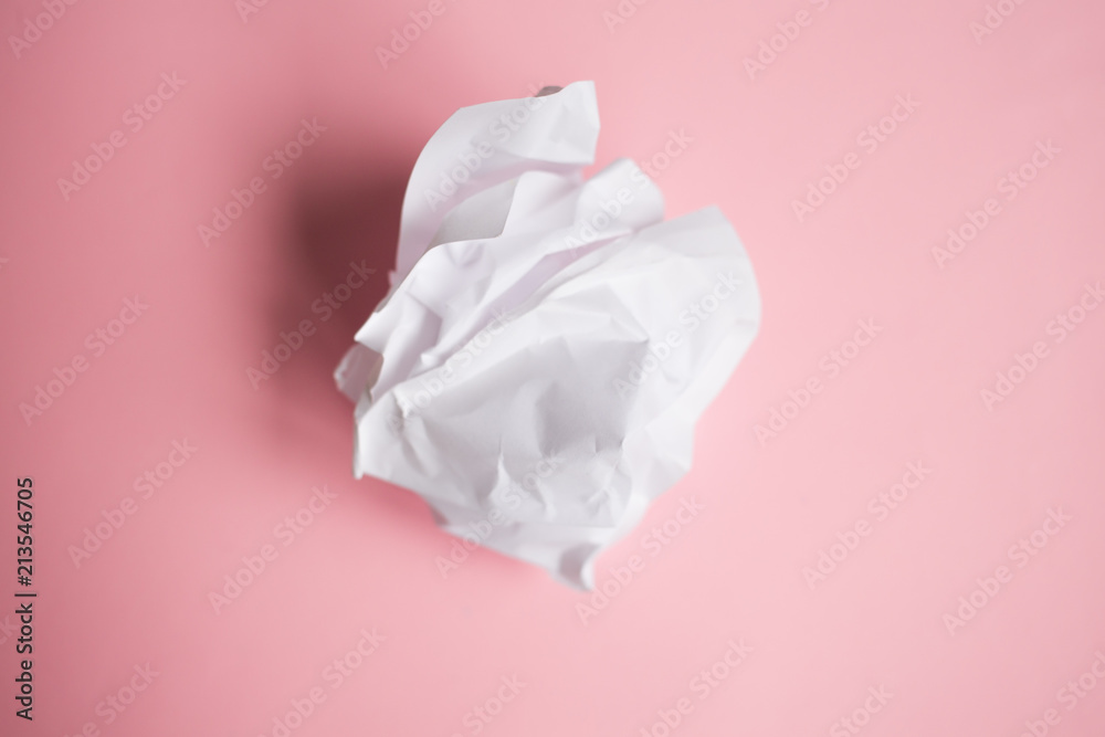 crumpled a white sheet of paper on the pink background