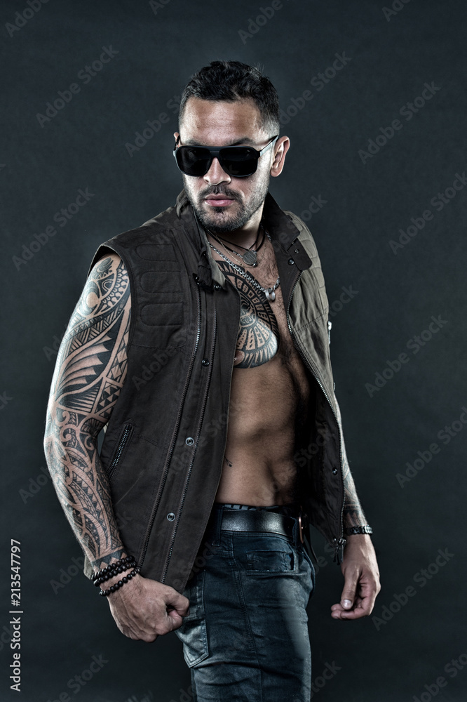 Tattooed man with six pack and ab. Bearded man with tattoo on chest and arms. Tattoo model with beard on unshaven face. Fashion style and trend. Fashion macho in trendy sunglasses, vintage filter Tattooed man with six pack and ab. Bearded man with tattoo on chest and arms. Tattoo model with beard on unshaven face. Fashion style and trend. Fashion macho in trendy sunglasses, vintage filter