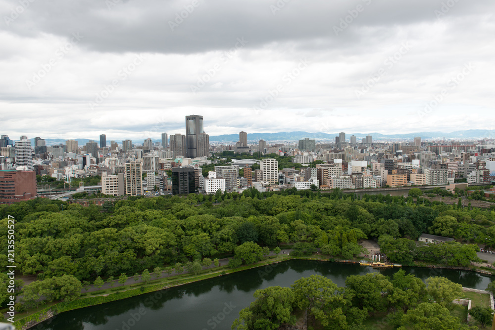 Aerial view of moat around castle park, Osaka business district and spectacular mountains surrounding the city from Osaka Castle.
