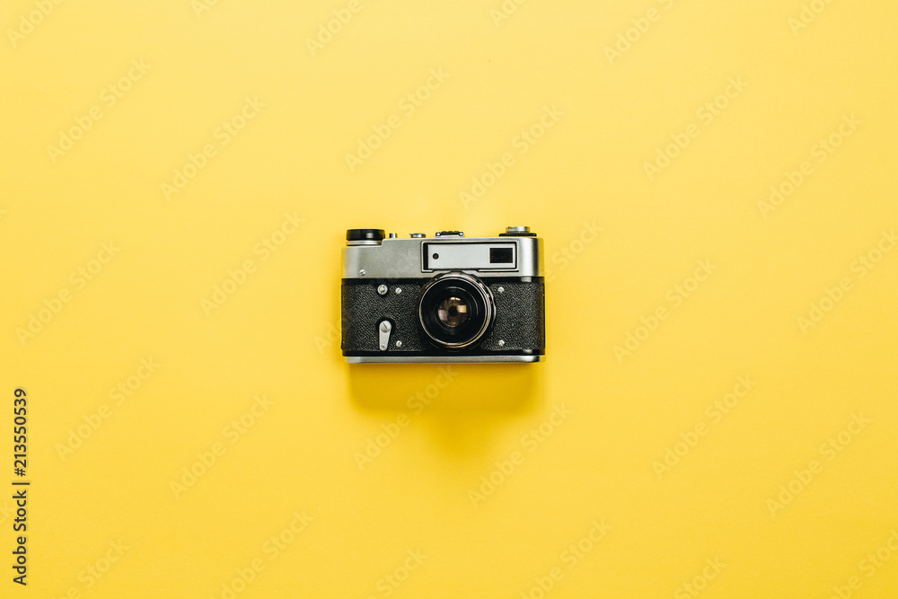 Fototapeta premium Vintage retro camera on yellow background. Flat lay, top view.