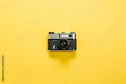 Vintage retro camera on yellow background. Flat lay, top view.