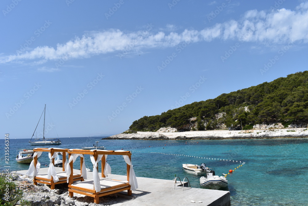 Tropical style wooden beach cabanas on the jetty of island of Hvar Croatia in summer. Adriatic ambience offers stunning views of the bay. The exciting nightlife of Hvar town is a leisurely walk away. 