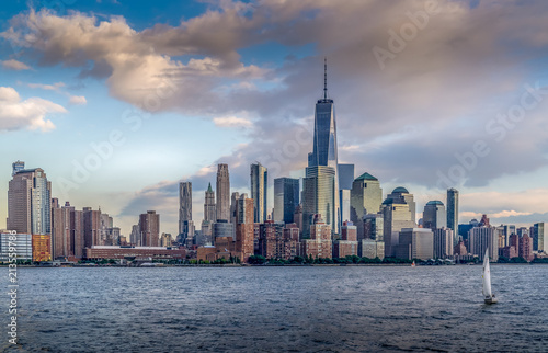 Panorama view of NYC Lower Manhattan skyline with cruise ship passing by on Hudson River.