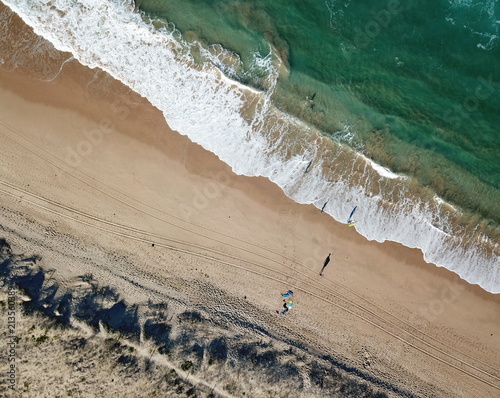Seascape with waves and shadows of walking people. Top view aerial photo from flying drone of nature landscape turquoise water with Wanda beach in winter day in Cronulla. Travel vacation concept.
