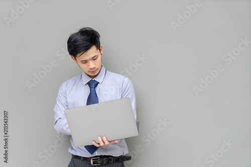 Business man in shirt adjust tie. Portrait young Asian man adjusting his necktie while standing against grey background. Morning dress up. Confident businessman in shirt. people, business, fashion.