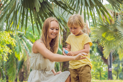 Mom and son use mosquito spray.Spraying insect repellent on skin outdoor photo