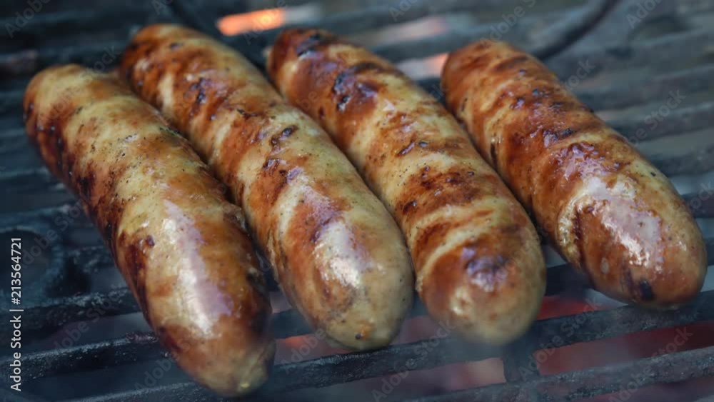 Closeup of four sausages with grill marks and smoking on a hot grill. Closeup of four sausages with grill marks and smoking on a hot grill.