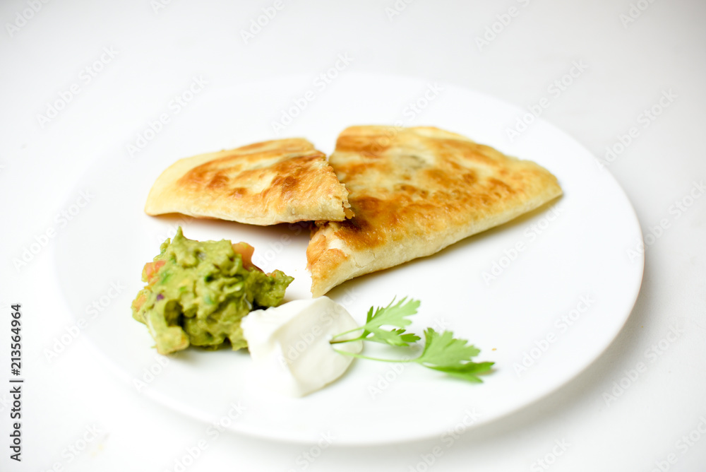 Mexican quesadilla with chicken, sour cream for dipping and guacamole isolated on white background