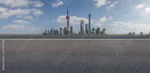 The empty asphalt road is built along modern commercial buildings in China's cities.