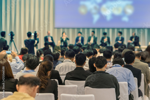 Speakers on the stage with Rear view of Audience in the conference hall or seminar meeting, business and education about investment concept