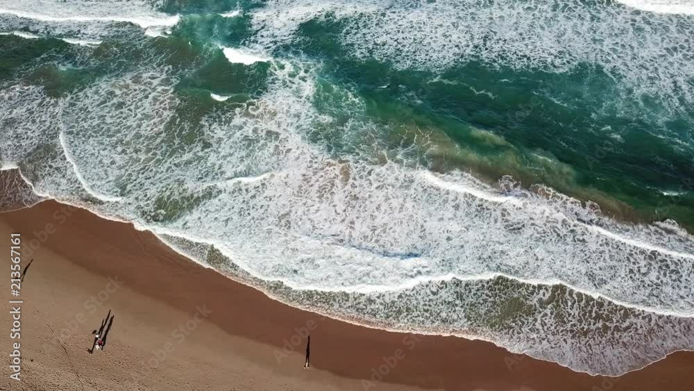 Seascape with waves and shadows of walking people. Top view aerial photo from flying drone of nature landscape turquoise water with Wanda beach in winter day in Cronulla. Travel vacation concept.