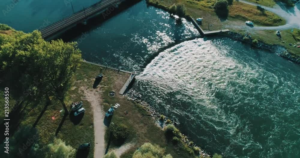 Huge River Waves getting surfed with small town and bridge in background