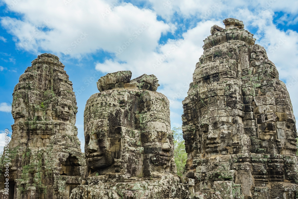 Ancient stone faces at blue sky cloudy of Bayon temple, Angkor Wat, Siam Reap, Cambodia.